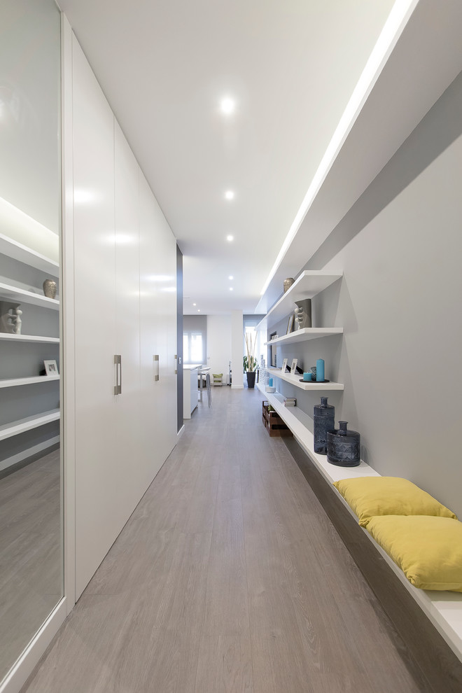 Idée de décoration pour un grand couloir minimaliste avec un mur gris et un sol en bois brun.