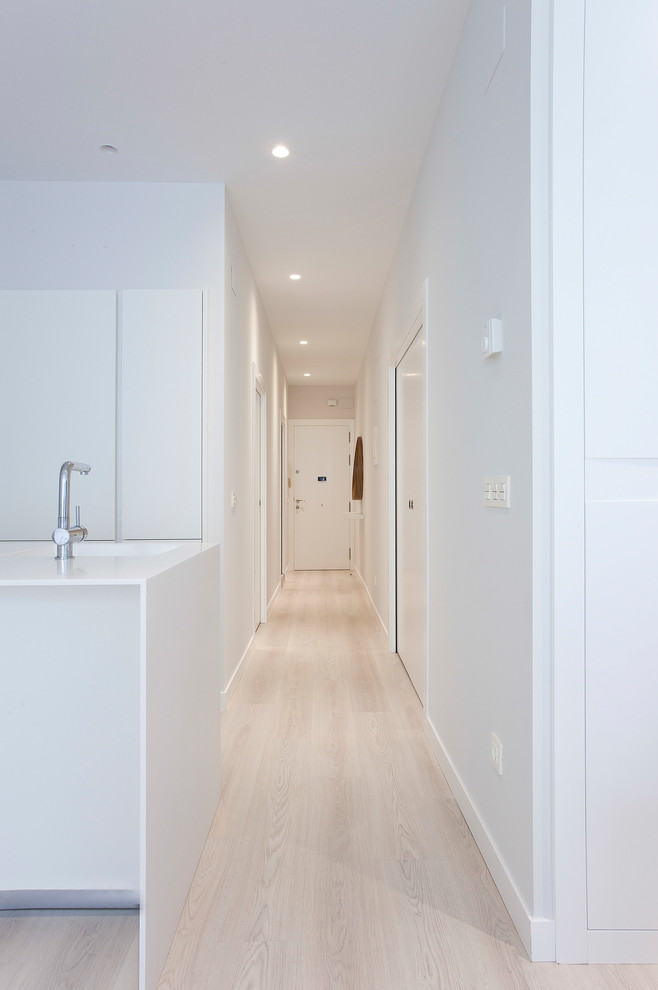 Idée de décoration pour un grand couloir design avec un mur blanc, parquet clair et un sol beige.