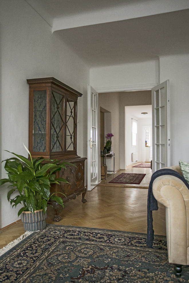 Modelo de recibidores y pasillos clásicos renovados de tamaño medio con paredes blancas y suelo de madera en tonos medios