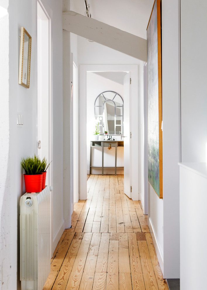 Ejemplo de recibidores y pasillos bohemios de tamaño medio con paredes blancas, suelo de madera en tonos medios y suelo marrón