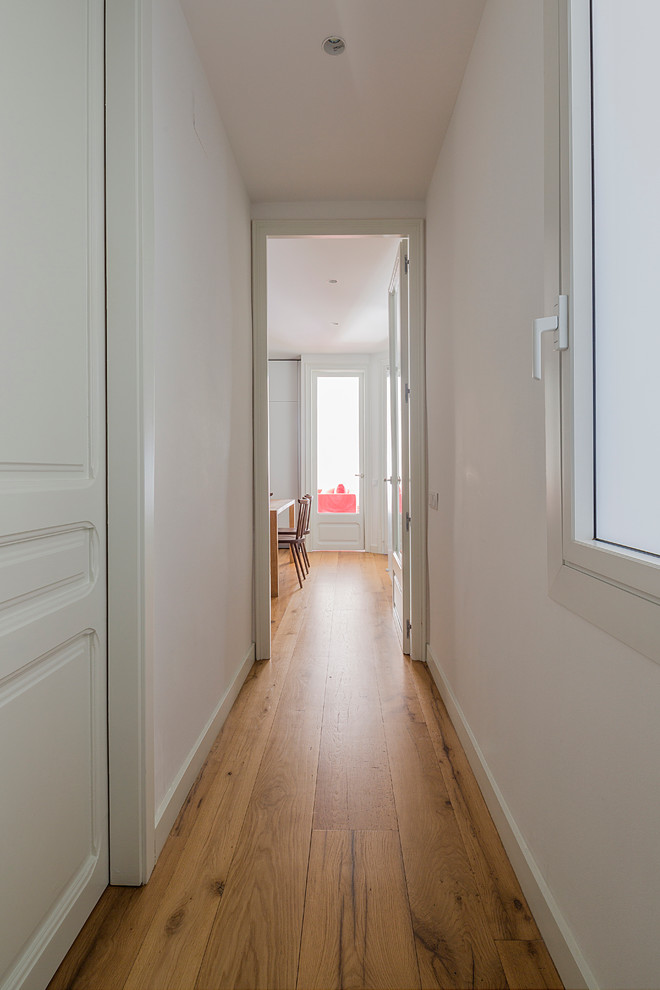 На фото: коридор среднего размера в скандинавском стиле с белыми стенами и паркетным полом среднего тона с