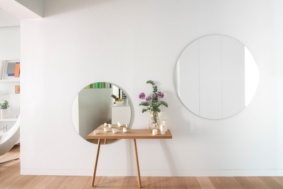 Cette image montre un couloir nordique de taille moyenne avec un mur blanc et parquet clair.