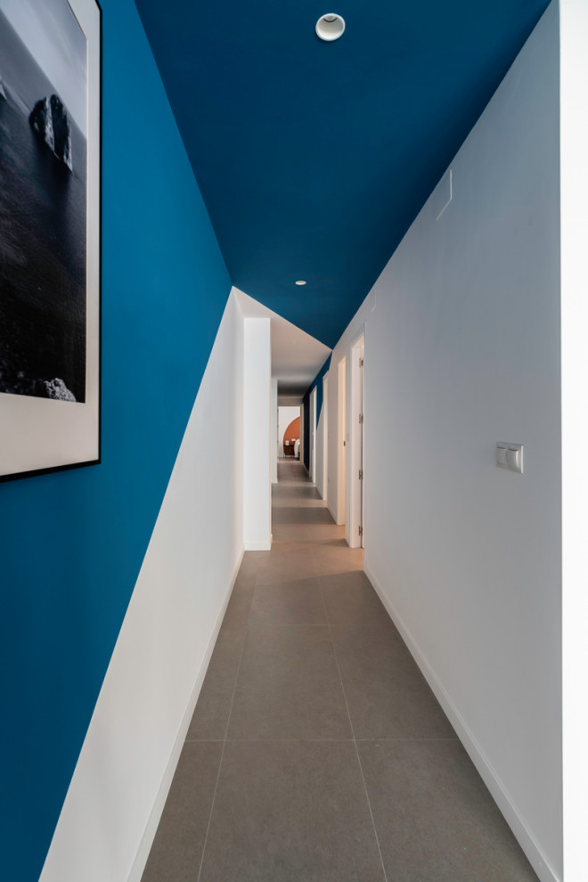 Diseño de recibidores y pasillos contemporáneos de tamaño medio con paredes azules, suelo de baldosas de porcelana y suelo gris