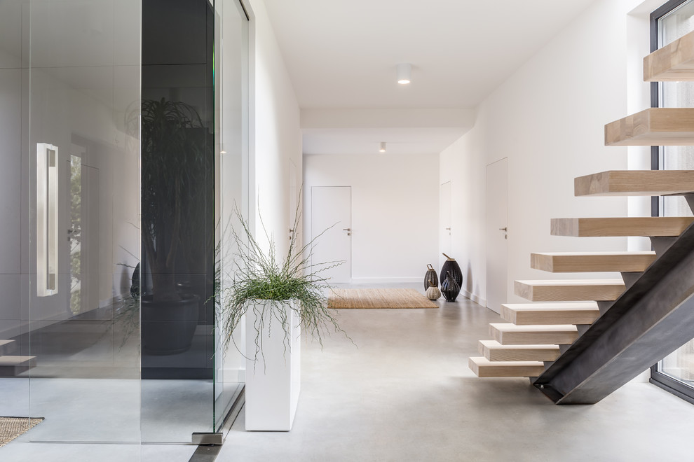 Ejemplo de recibidores y pasillos minimalistas con paredes blancas, suelo de cemento y suelo gris