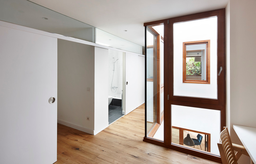 Imagen de recibidores y pasillos contemporáneos de tamaño medio con paredes blancas, suelo de madera en tonos medios y suelo marrón