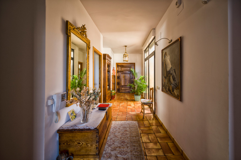 Источник вдохновения для домашнего уюта: большой коридор в средиземноморском стиле с белыми стенами, полом из терракотовой плитки и красным полом