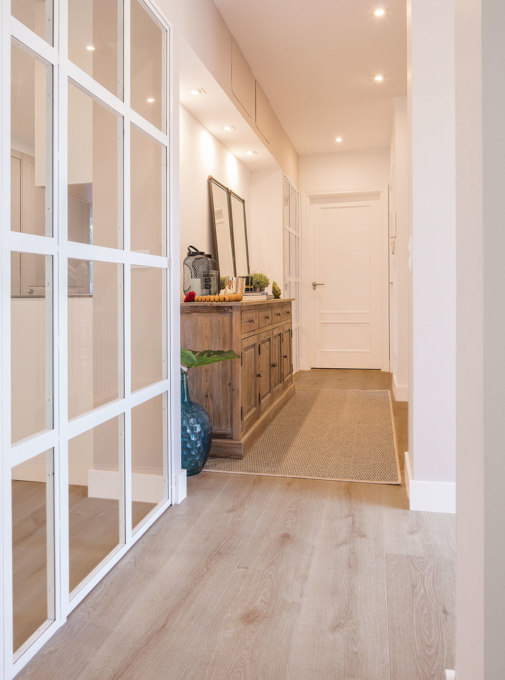 Idée de décoration pour un couloir minimaliste de taille moyenne avec un mur blanc, parquet clair et un sol marron.