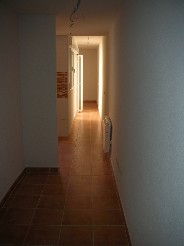 Idée de décoration pour un petit couloir minimaliste avec un mur blanc, un sol en carrelage de céramique et un sol marron.