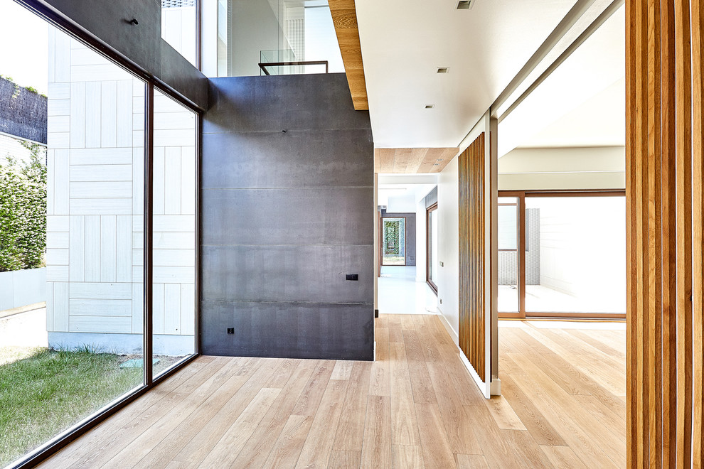 Aménagement d'un grand couloir moderne avec un mur blanc et un sol en bois brun.