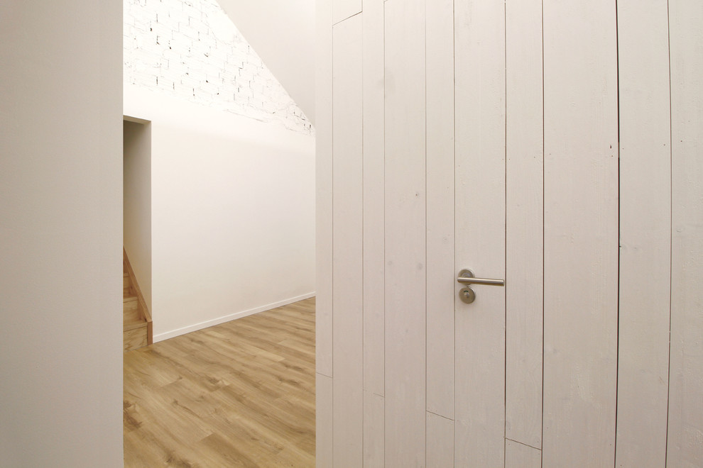Idée de décoration pour un couloir nordique avec un mur blanc, parquet clair et un sol marron.