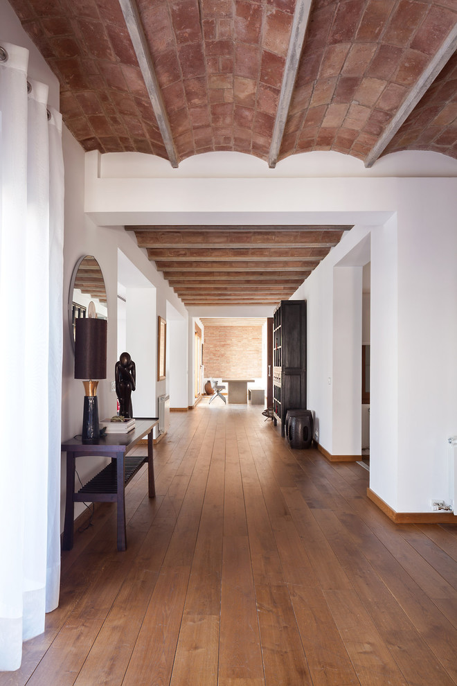 Immagine di un ingresso o corridoio mediterraneo con pareti bianche, pavimento in legno massello medio e pavimento marrone