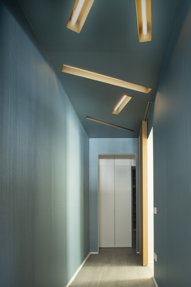 Réalisation d'un couloir design de taille moyenne avec un mur bleu, un sol en carrelage de porcelaine et un sol gris.