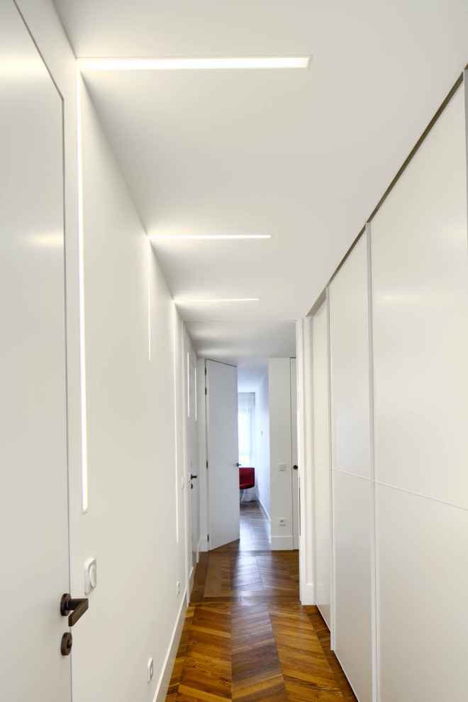 Huge trendy medium tone wood floor and brown floor hallway photo in Other with white walls
