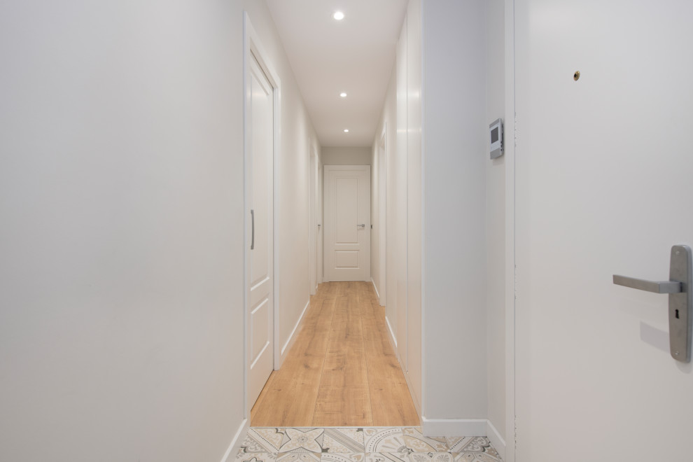 Пример оригинального дизайна: большой коридор в стиле модернизм с белыми стенами, полом из ламината и коричневым полом