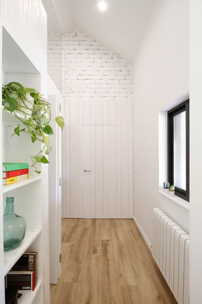 Foto de recibidores y pasillos escandinavos pequeños con paredes blancas, suelo laminado y suelo marrón