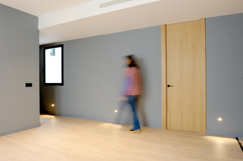 Inspiration pour un grand couloir design avec un mur bleu et un sol en bois brun.