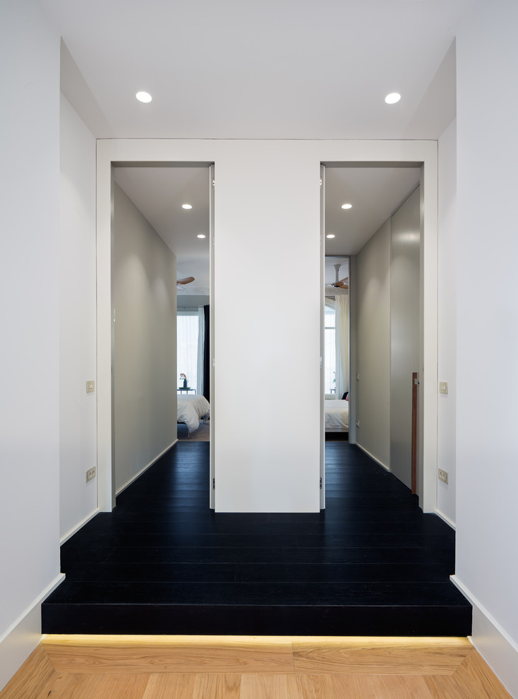 Diseño de recibidores y pasillos actuales con paredes blancas, suelo de madera pintada y suelo negro
