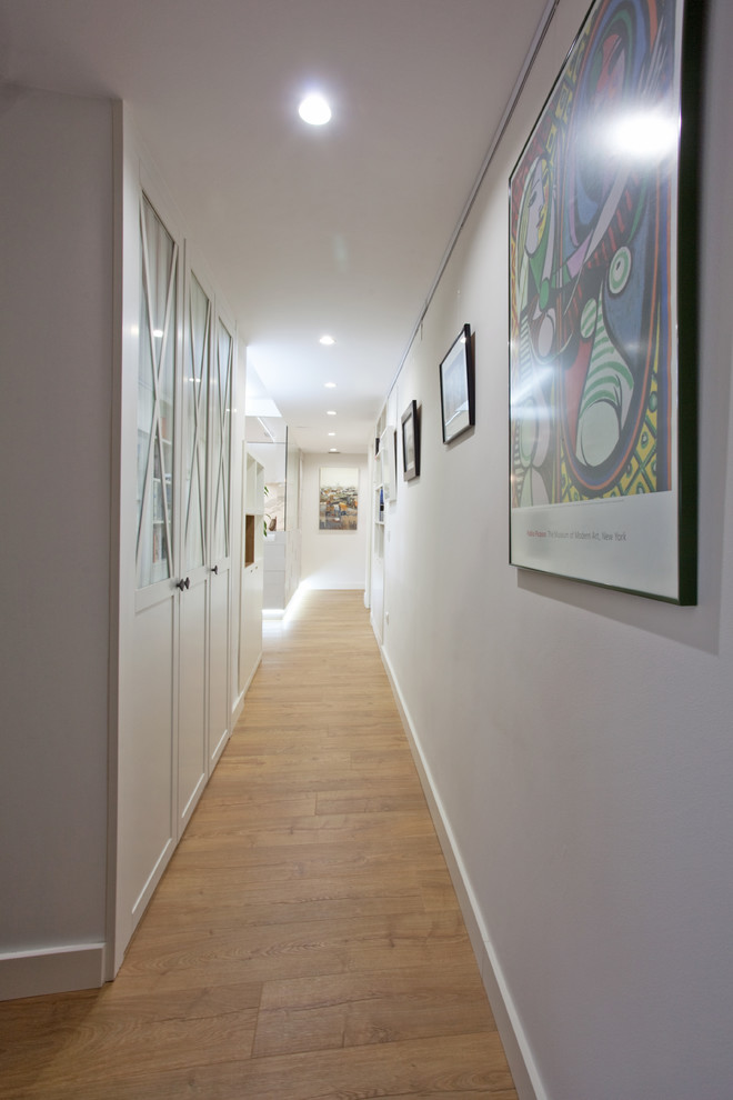Réalisation d'un couloir design de taille moyenne avec un mur blanc et sol en stratifié.