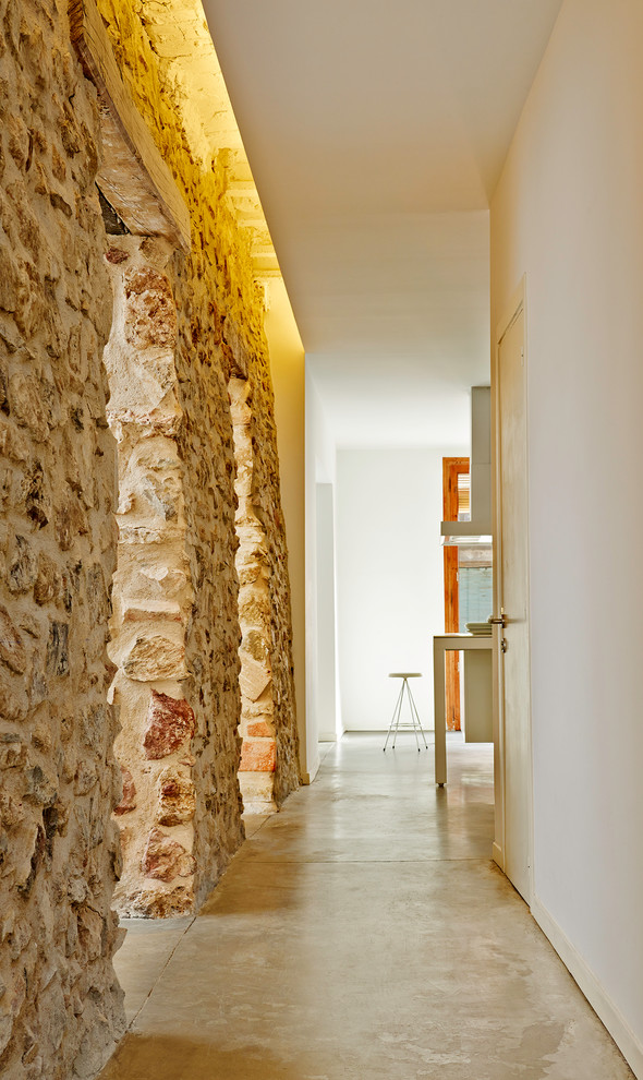 Idées déco pour un grand couloir contemporain avec un mur blanc et sol en béton ciré.