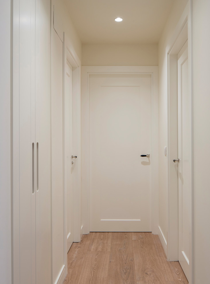 На фото: коридор среднего размера в стиле неоклассика (современная классика) с бежевыми стенами, полом из ламината и коричневым полом