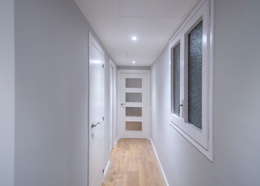Ejemplo de recibidores y pasillos actuales de tamaño medio con paredes grises, suelo de madera en tonos medios y suelo marrón