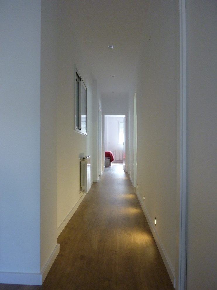 Cette photo montre un petit couloir scandinave avec un mur blanc et un sol marron.