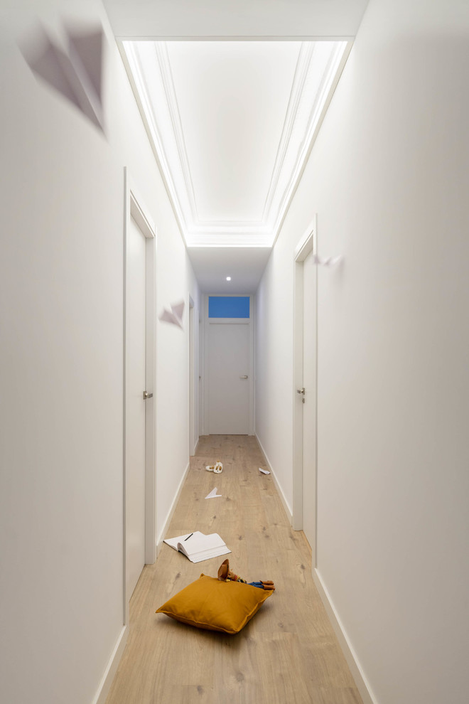 Cette photo montre un grand couloir chic avec un mur blanc, sol en stratifié et un sol marron.