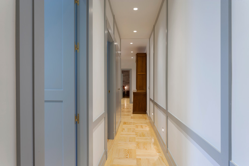 Modelo de recibidores y pasillos tradicionales renovados de tamaño medio con paredes blancas y suelo de madera clara