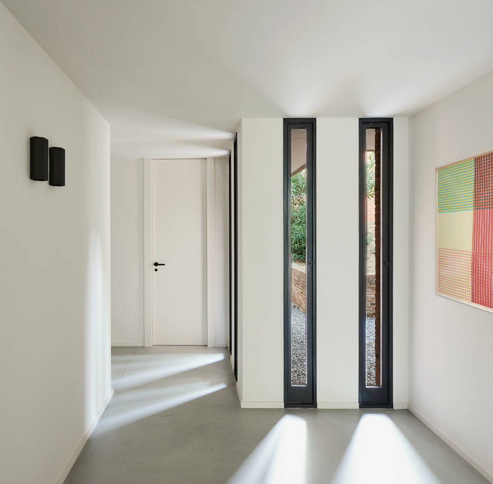 Idées déco pour un grand couloir moderne avec un mur beige, sol en béton ciré et un sol gris.