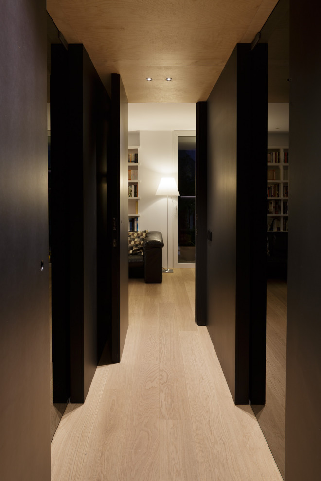 Idées déco pour un couloir contemporain de taille moyenne avec un mur noir, un sol en bois brun et un sol marron.