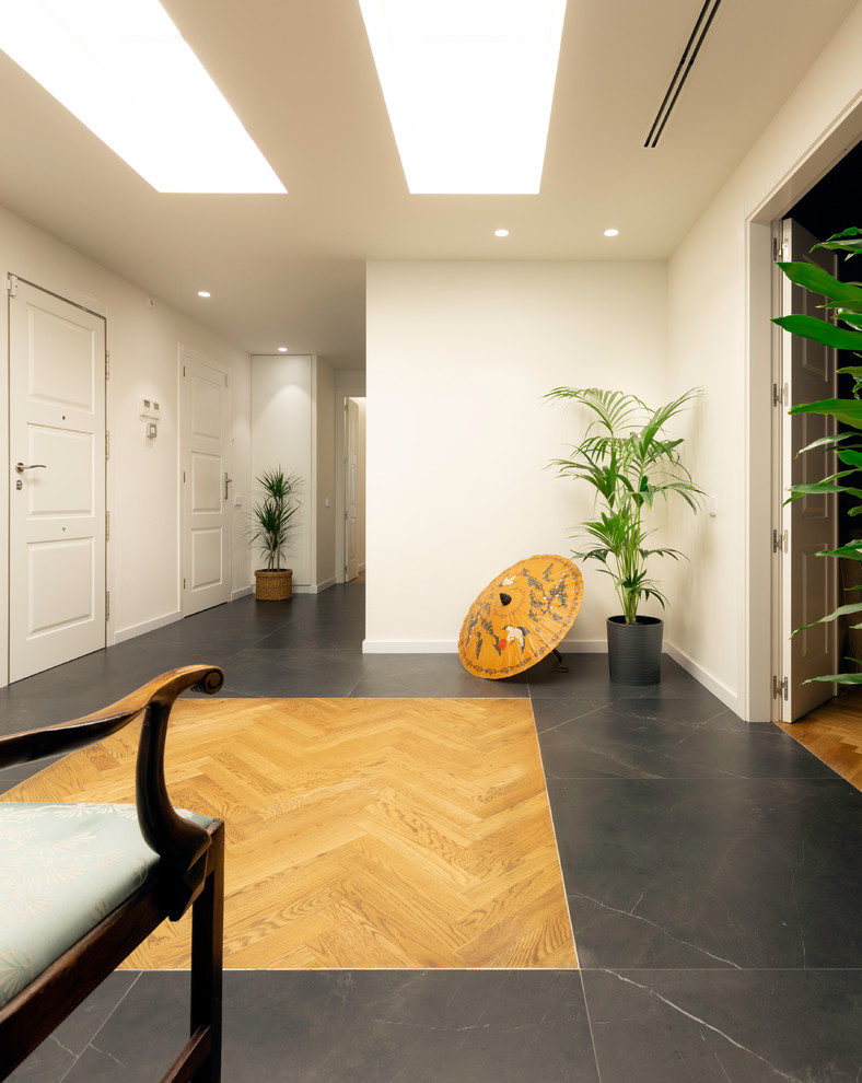 Exemple d'un grand couloir tendance avec un mur blanc, un sol en bois brun et un sol marron.