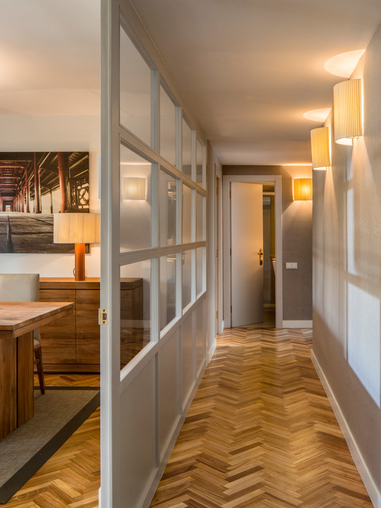 Diseño de recibidores y pasillos de tamaño medio con paredes blancas, suelo de madera en tonos medios y suelo marrón