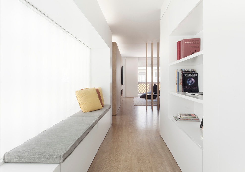 Idéer för att renovera en mellanstor minimalistisk hall, med vita väggar och ljust trägolv