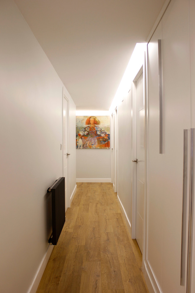 Imagen de recibidores y pasillos actuales de tamaño medio con paredes blancas y suelo de madera en tonos medios