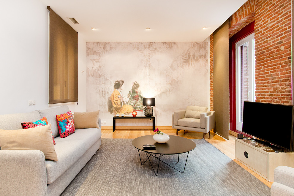 Immagine di un soggiorno etnico con TV autoportante, pareti bianche, parquet chiaro e nessun camino