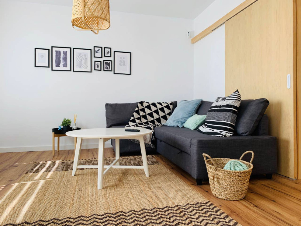 Diseño de sala de estar abierta nórdica de tamaño medio con paredes blancas y suelo laminado