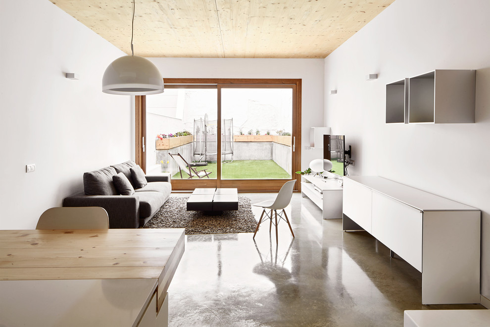 Modelo de sala de estar abierta escandinava de tamaño medio sin chimenea con paredes blancas, suelo de cemento y televisor colgado en la pared