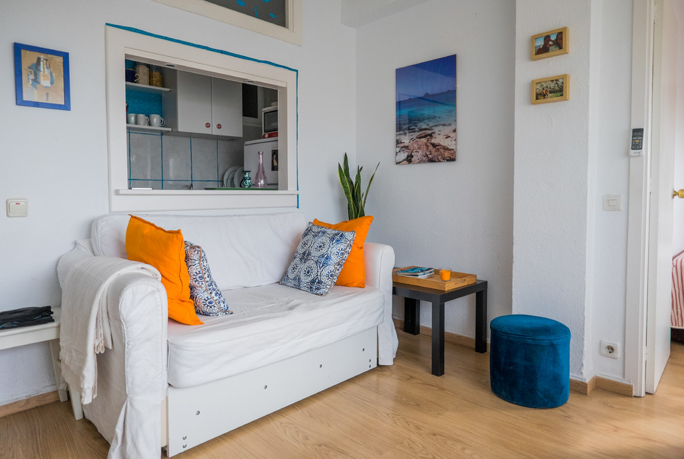 Diseño de sala de estar cerrada mediterránea pequeña sin chimenea y televisor con paredes blancas y suelo de madera en tonos medios