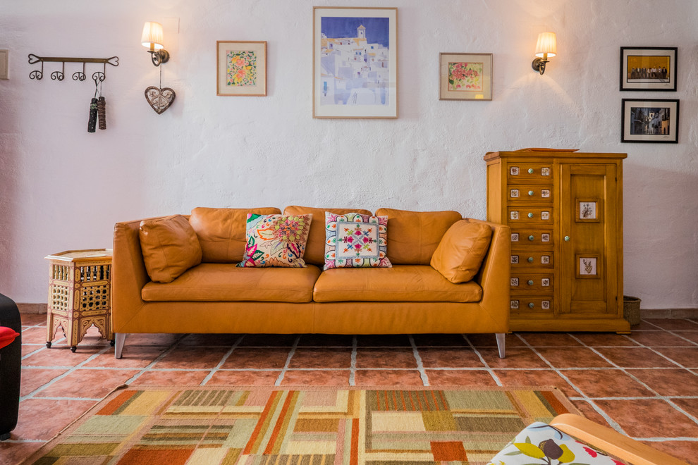 Diseño de sala de estar cerrada mediterránea de tamaño medio sin chimenea y televisor con paredes blancas y suelo de baldosas de terracota
