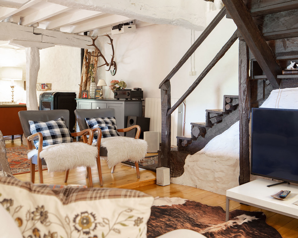 Imagen de sala de estar con rincón musical abierta rural de tamaño medio con paredes blancas, suelo de madera clara, televisor independiente y suelo marrón