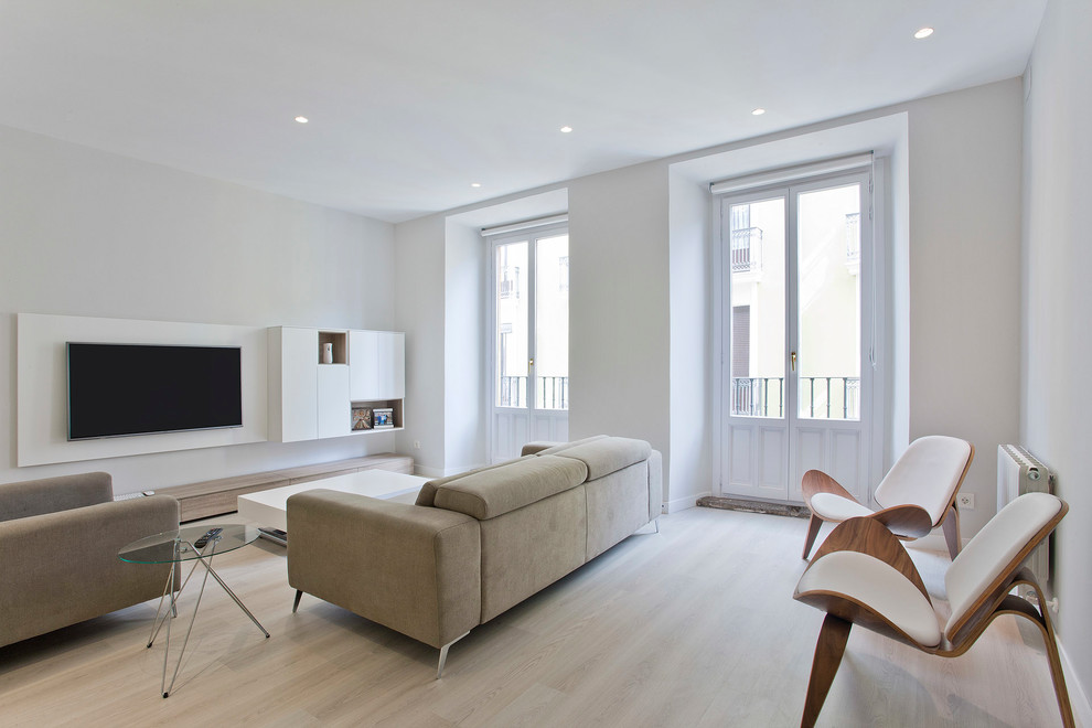 Diseño de sala de estar abierta actual de tamaño medio sin chimenea con paredes blancas, suelo de madera clara, televisor colgado en la pared y suelo beige