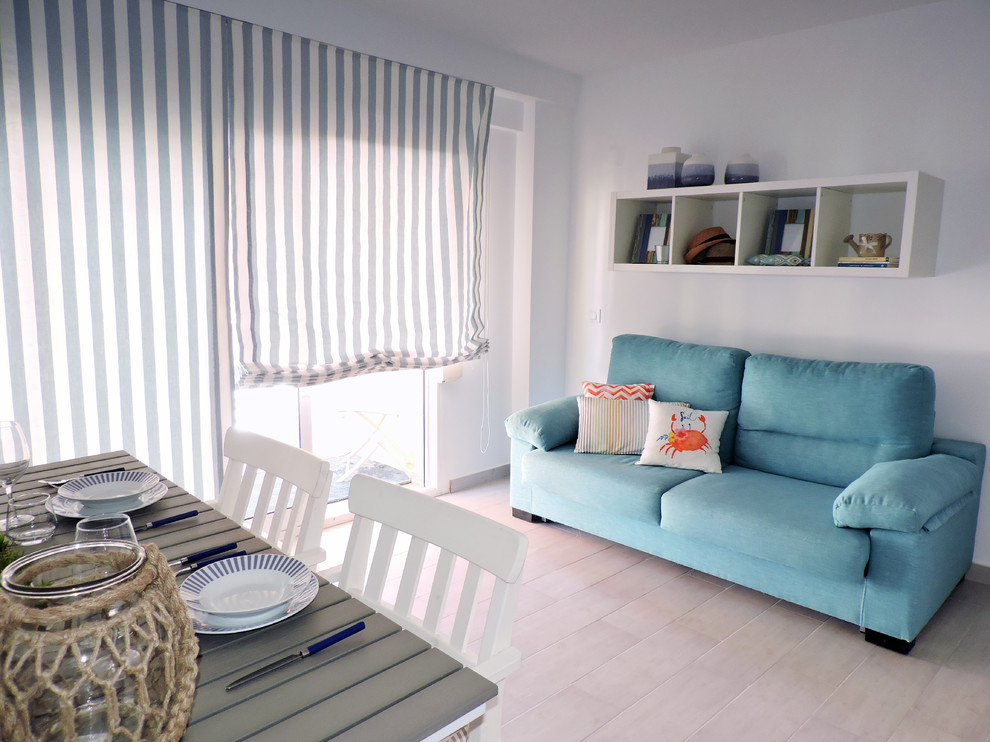 Cette image montre une petite salle de séjour méditerranéenne ouverte avec un mur blanc, un sol en carrelage de céramique, un téléviseur fixé au mur et un sol beige.
