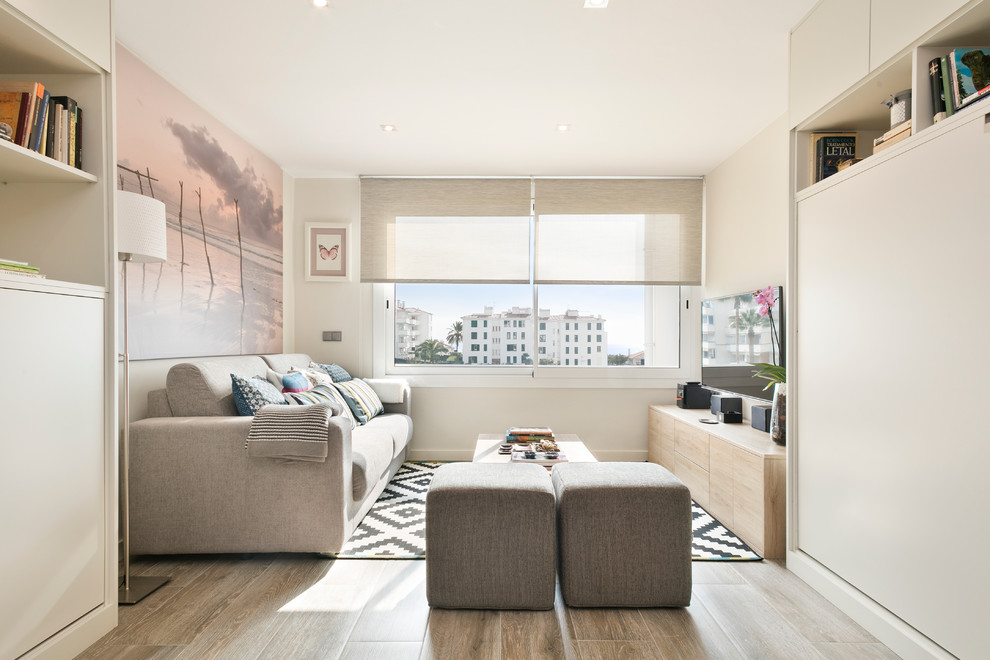 На фото: маленькая двухуровневая гостиная комната в стиле модернизм с белыми стенами, полом из керамогранита и телевизором на стене для на участке и в саду с