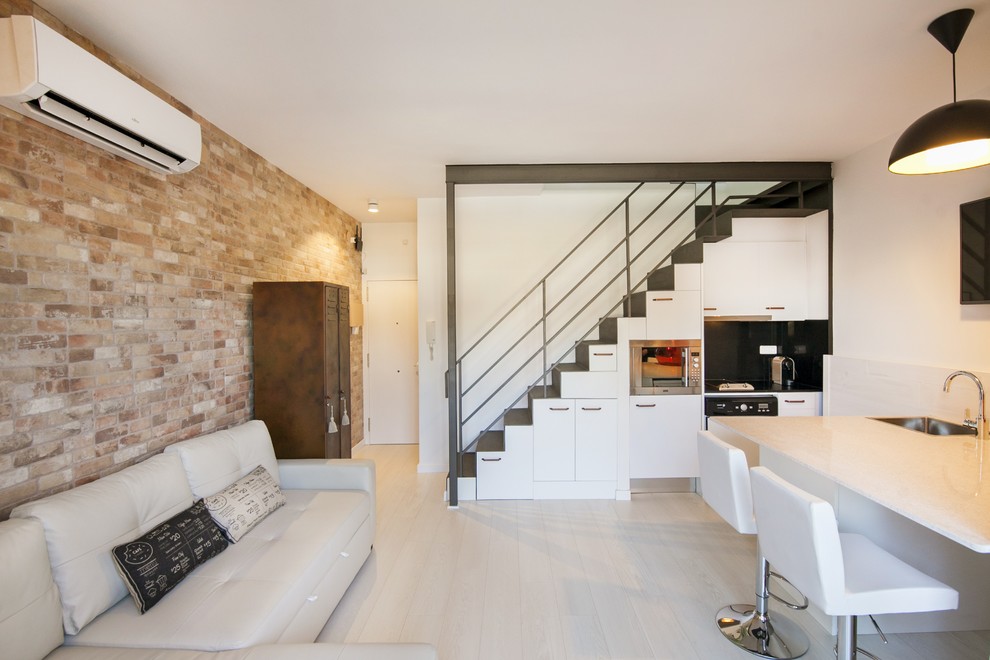 Ejemplo de sala de estar abierta actual pequeña con paredes blancas, suelo de madera clara y televisor colgado en la pared