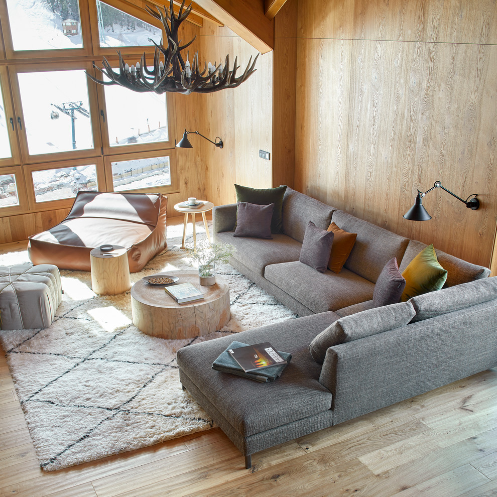 Imagen de sala de estar abierta moderna grande con suelo de madera en tonos medios, chimenea de doble cara y marco de chimenea de metal