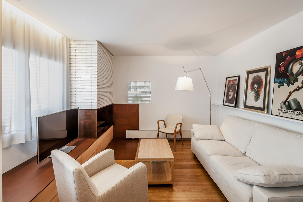 Modernes Wohnzimmer mit weißer Wandfarbe, braunem Holzboden, Kamin und freistehendem TV in Sonstige