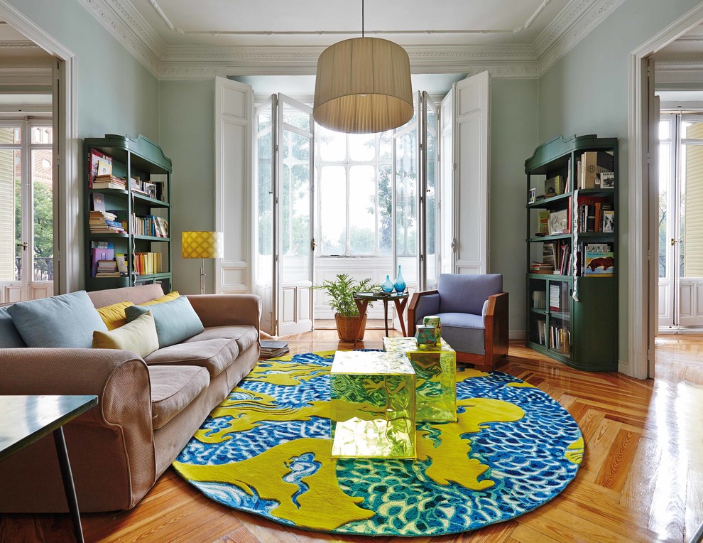 Ejemplo de sala de estar con biblioteca cerrada ecléctica de tamaño medio sin chimenea con paredes azules y suelo de madera en tonos medios