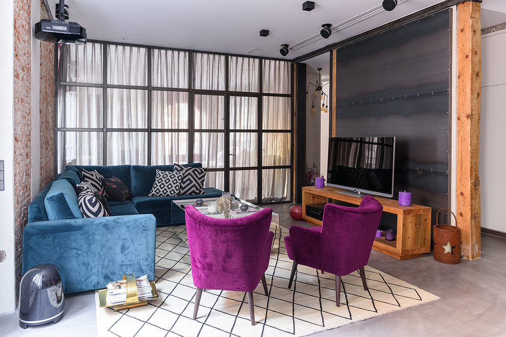 На фото: гостиная комната в современном стиле с бетонным полом, отдельно стоящим телевизором, серым полом и синим диваном без камина