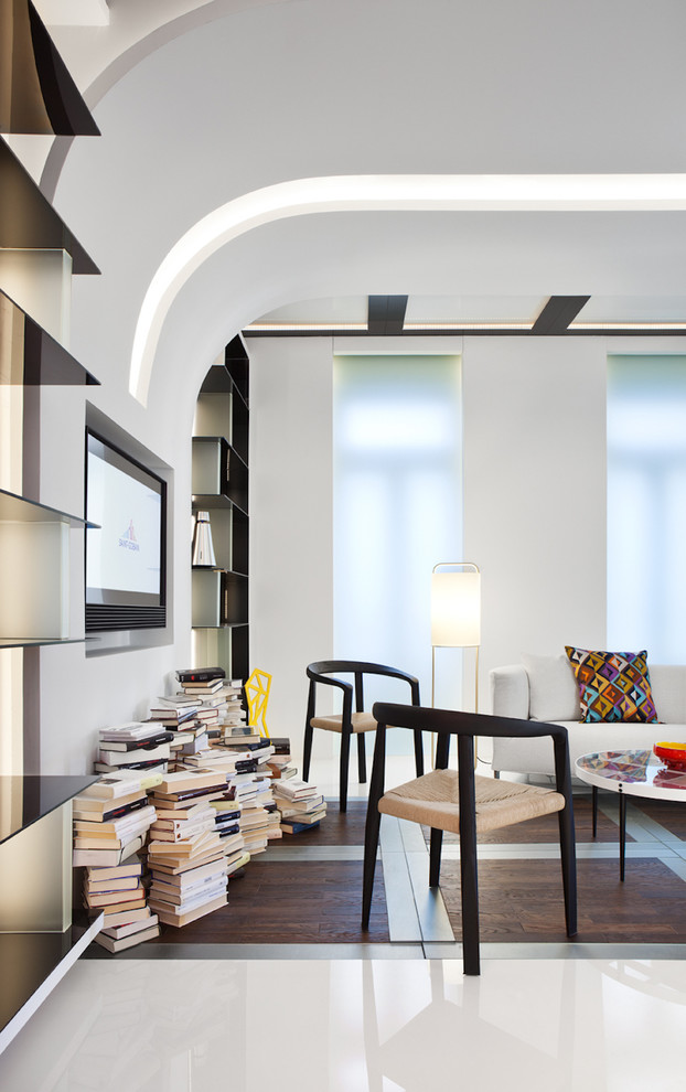 Идея дизайна: гостиная комната в стиле модернизм с с книжными шкафами и полками, белыми стенами и телевизором на стене