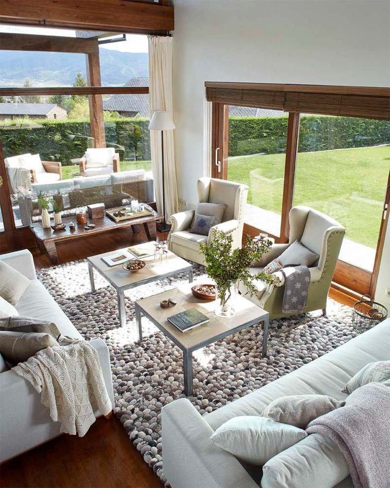 Imagen de sala de estar abierta campestre grande sin chimenea y televisor con paredes blancas y suelo de madera oscura